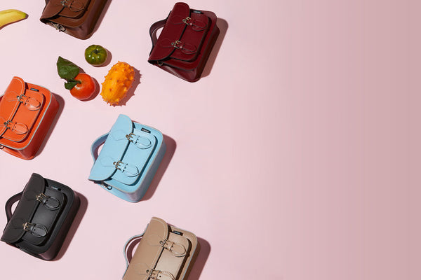 colourful assortment of handmade leather micro satchels on a pink background