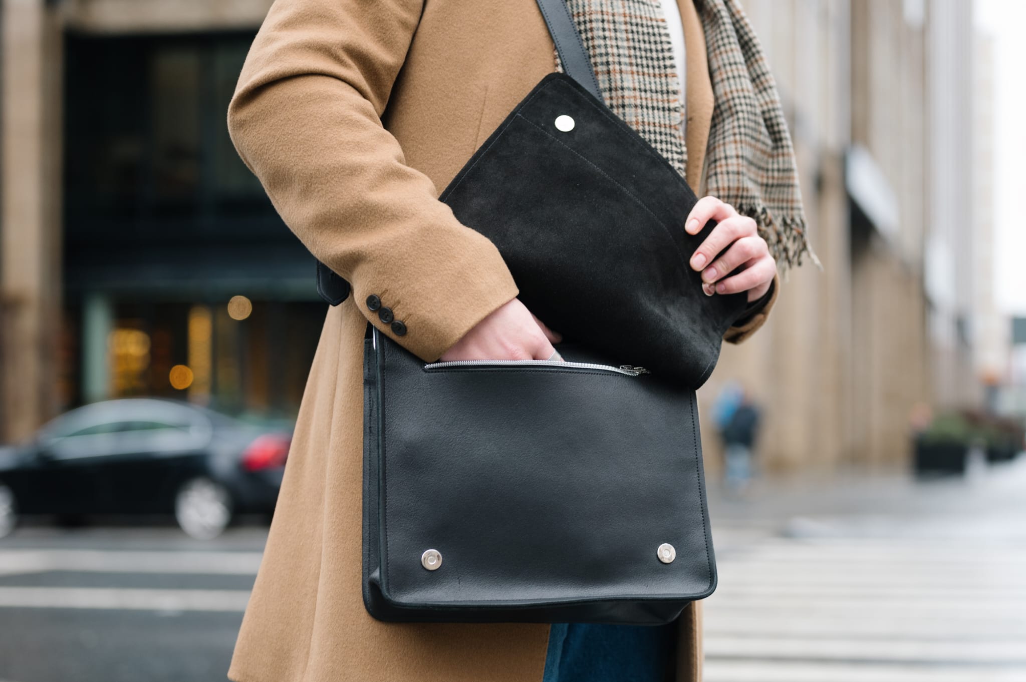 man putting hand in pocket of leather messenger bag