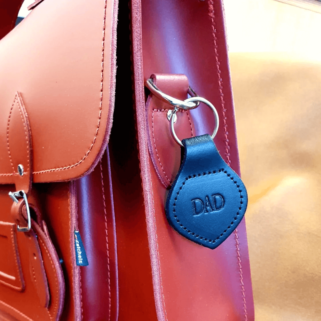 man holding handmade leather city backpack in black whilst leaning against a wall