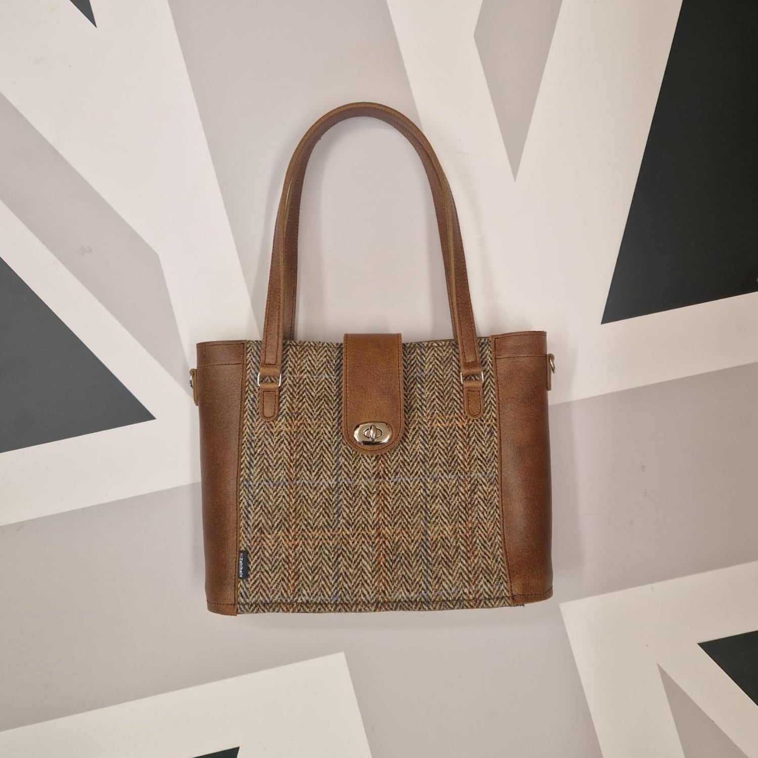 Brown handbag with patterned front section on a geometric background