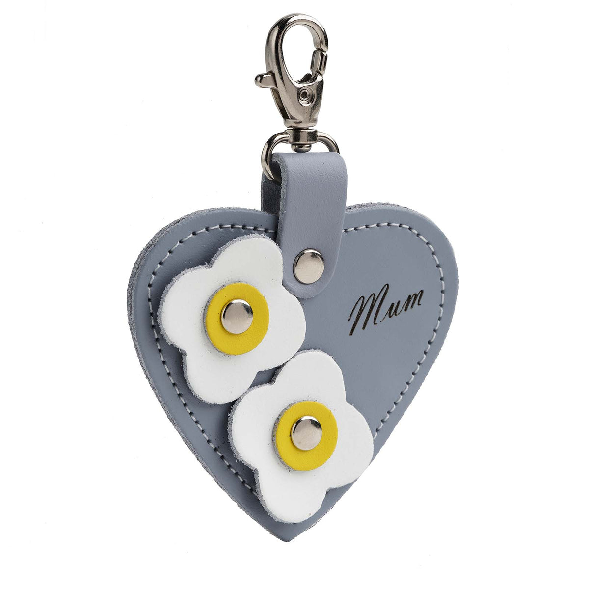 A lilac grey leather heart-shaped bag charm with white flower appliques and the engraved text 'MUM'.