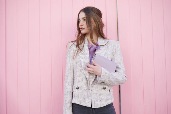 Model wearing Zatchels Handmade Leather Handbag in purple on a pink background