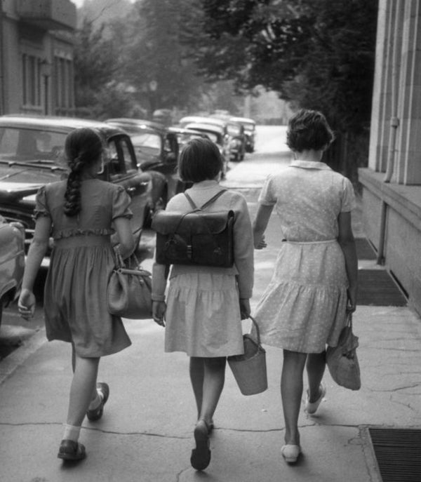 A black and white photo of school girls walking with satchels