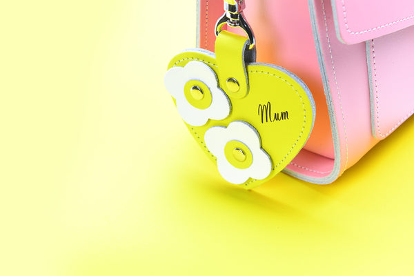 yellow heart charm that says 'mum' attached to a pink leather satchel