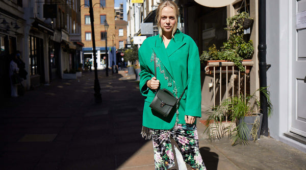 Model wearing Zatchels Handmade Leather Sugarcube Bag in green in an urban background
