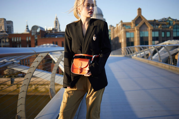 Woman with saddle bag handbag and blazer on a bridge