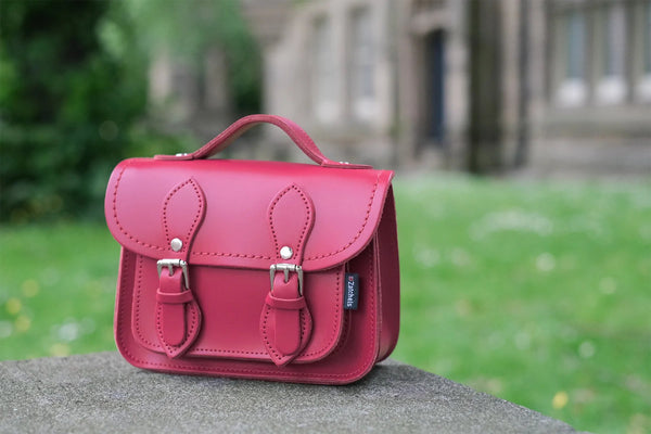 micro satchel in Red placed on a stone wall in a garden