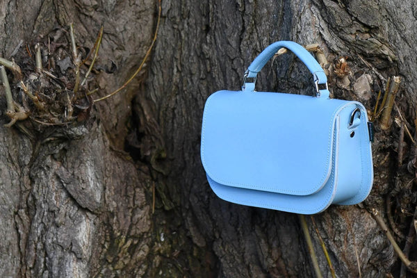Zatchels Aura handmade leather bag in blue placed on a tree trunk