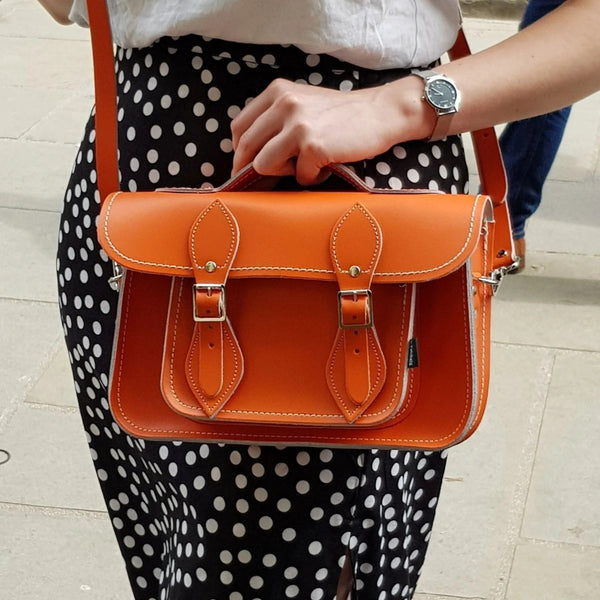 person wearing black and white polka dot skirt wearing orange handmade leather satchel