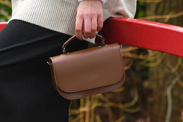 woman carrying Aura handmade leather clutch bag in brown