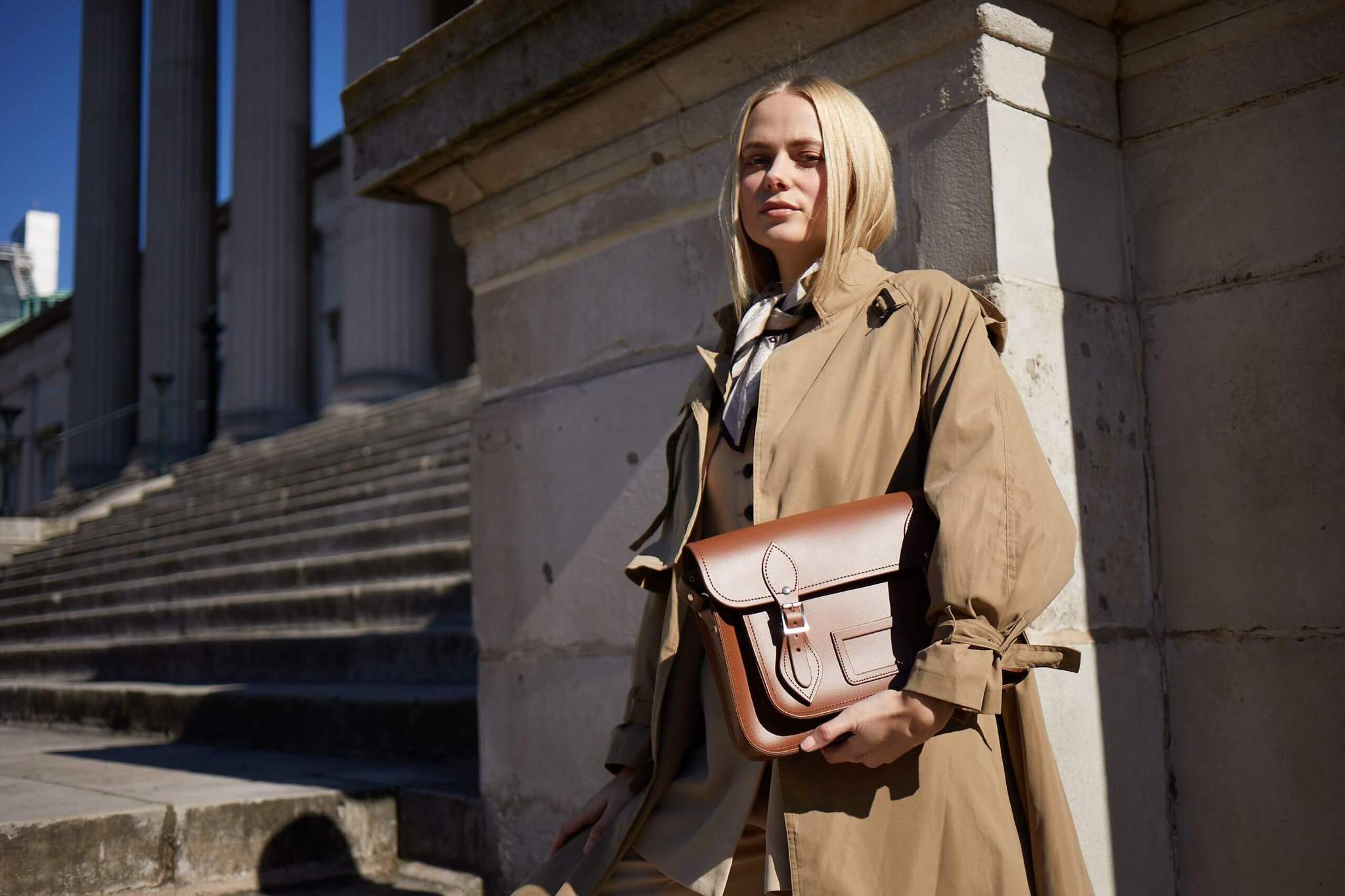 woman dressed in work wear holding handmade leather satchel in brown under her arm