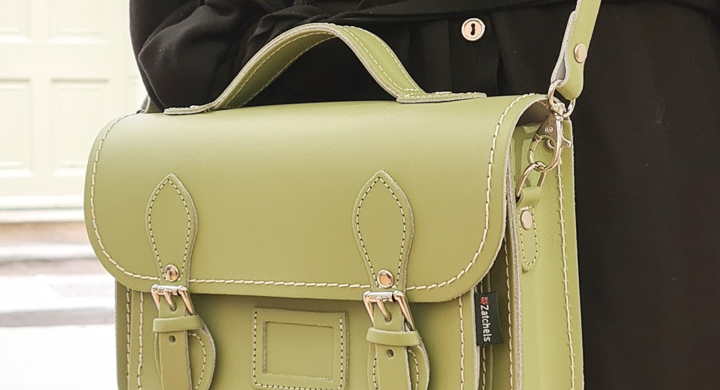 sage green satchel worn over black coat