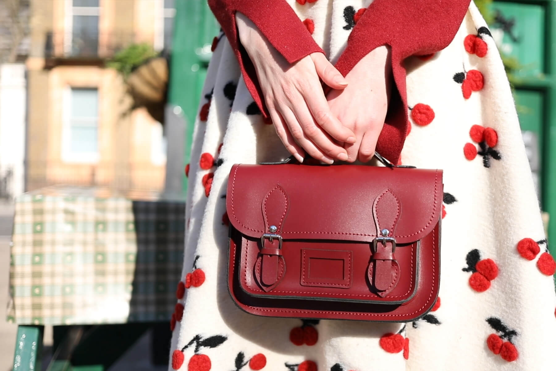 Person carrying Red micro satchel wearing red patterned skirt