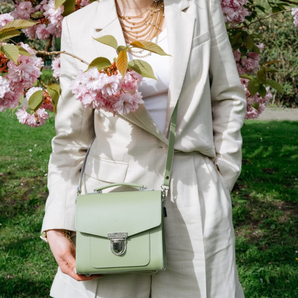 female wearing a sage green boxy handbag with cherry blossom in the foreground